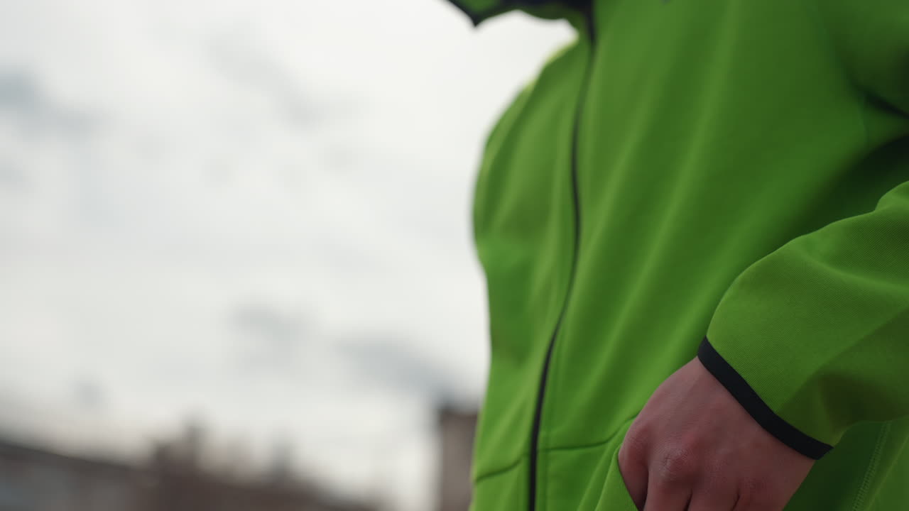 흐린 하늘 아래에서 지도를 보고 있는 남성, 초록색 후드티를 입고 도시 경로를 주의 깊게 확인하는 남성, 흰색 후드 스웨트셔츠를 입고 모바일 앱을 사용하여 도시 거리를 탐색하는 젊은 남성