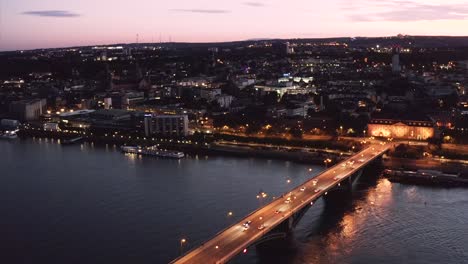 Crossing-bridge-shot-of-Mainz-by-a-drone-on-a-clear-evening-after-sunset-with-a-bit-of-glow-on-the-sky-and-reflections-on-the-Rhine-river-Water-with-a-Drohne