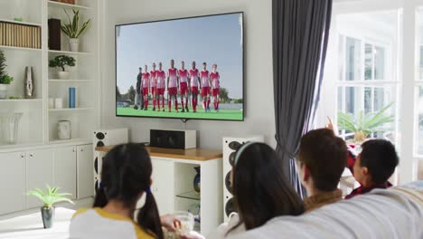 행복 한 가족 이 집 에서 함께 앉아 tv 에서 스포츠 이벤트 를 시청 하고 있는 사진