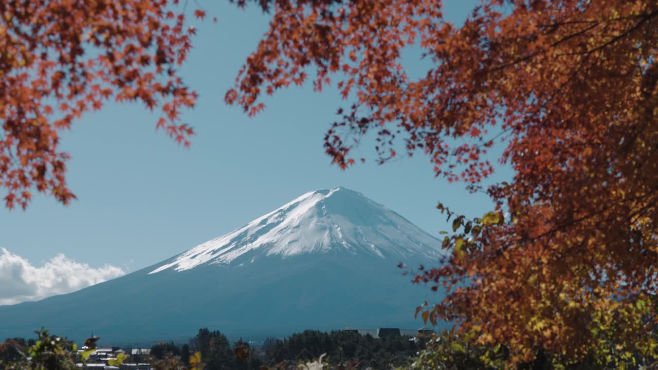 потрясающий наклонный кадр, изображающий величественную гору фудзи, возвышающуюся над озером кавагучико, в окружении ярко-красной осенней листьев.