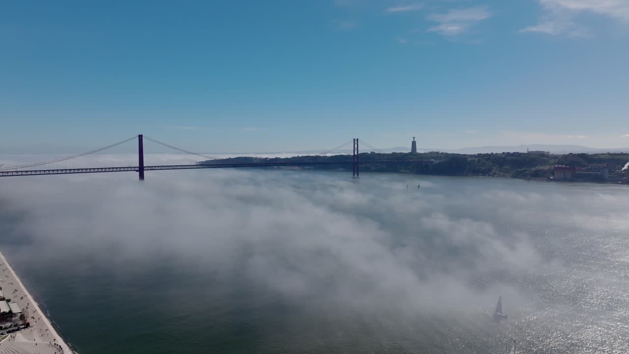 Static drone shot of the river and Ponte de 25 Abril, Portugal, in the fog.
