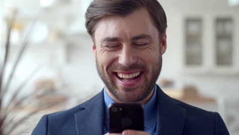 hombre de negocios alegre navegando por internet en el teléfono en casa. hombre enviando mensajes de texto en el teléfono.