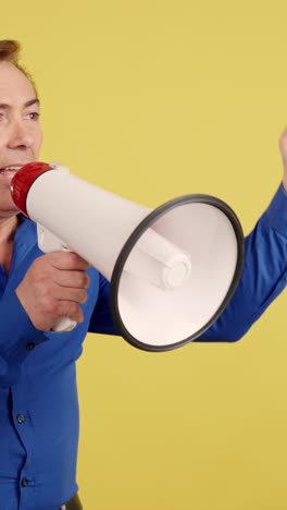 man shouting into a megaphone on yellow background