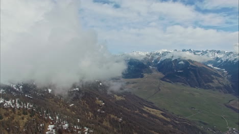 Aerial-Landscape-Views-of-Mountain-Range-Capped-with-Snow-and-Low-Clouds-Overhead