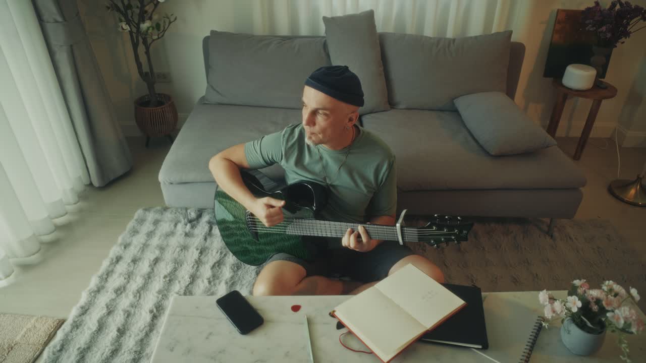 Mand spiller akustisk guitar og øver musik derhjemme