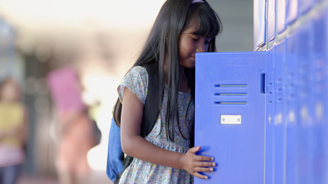 Biracial girl with long dark hair opens a locker at school