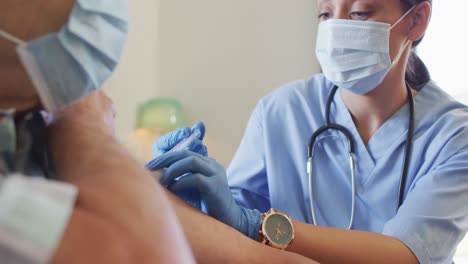 Video-of-hands-of-biracial-female-doctor-vaccinating-caucasian-senior-man