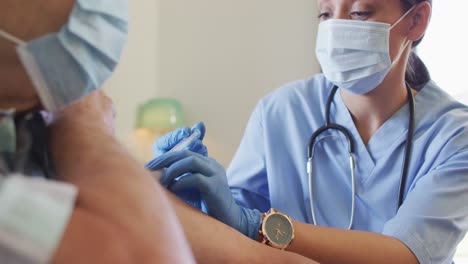 video de las manos de una doctora biracial vacunando a un hombre caucásico mayor