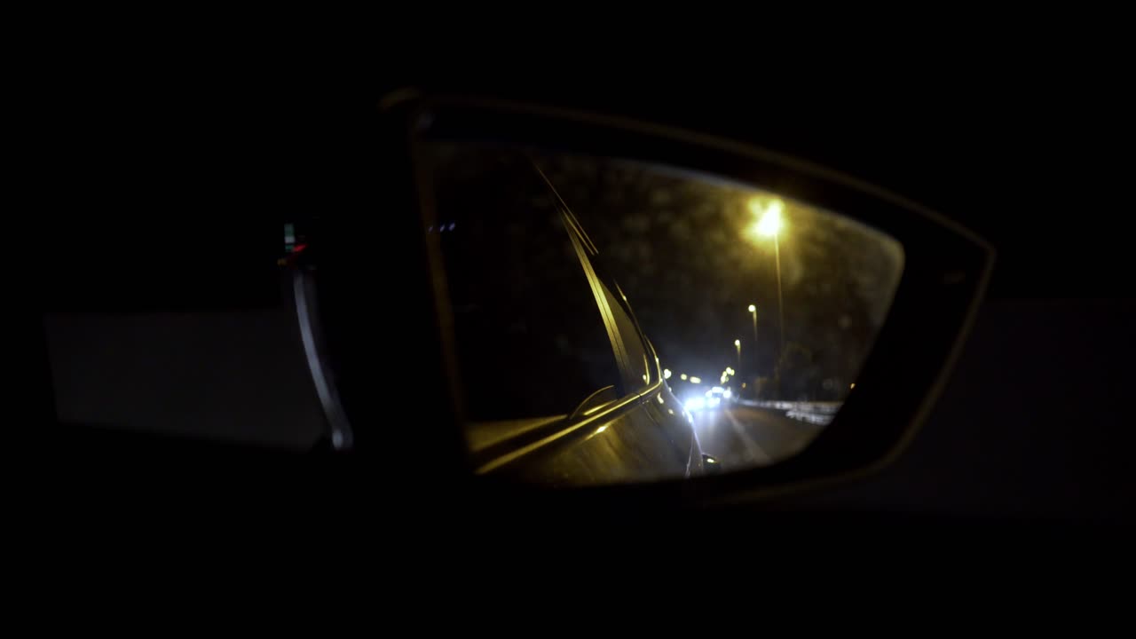 toma nocturna pov del espejo del pasajero del automóvil, conduciendo en la autopista 4k