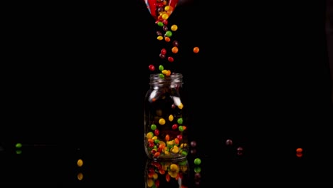 una bolsa de skittles que se vierte en un frasco de vidrio