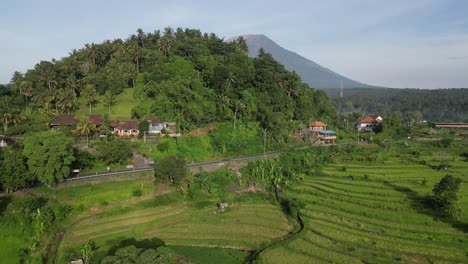 Drone-rising-over-a-small-hill-revealing-a-volcano-mountain-in-the-background