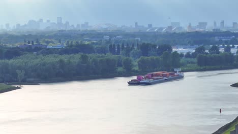 A-loaded-container-ship-sailing-on-River-Noord-under-a-hazy-and-grey-sky,-The-Netherlands