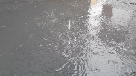 Gotas-De-Lluvia-Cayendo-En-Un-Charco-De-Agua-Del-Canalón-Del-Techo-Que-Se-Filtra-En-El-Callejón,-Imágenes-En-Cámara-Lenta