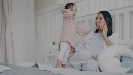 Mother talking on phone while toddler plays