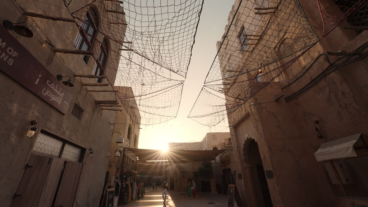A sunlit alleyway in an old town, covered with nets