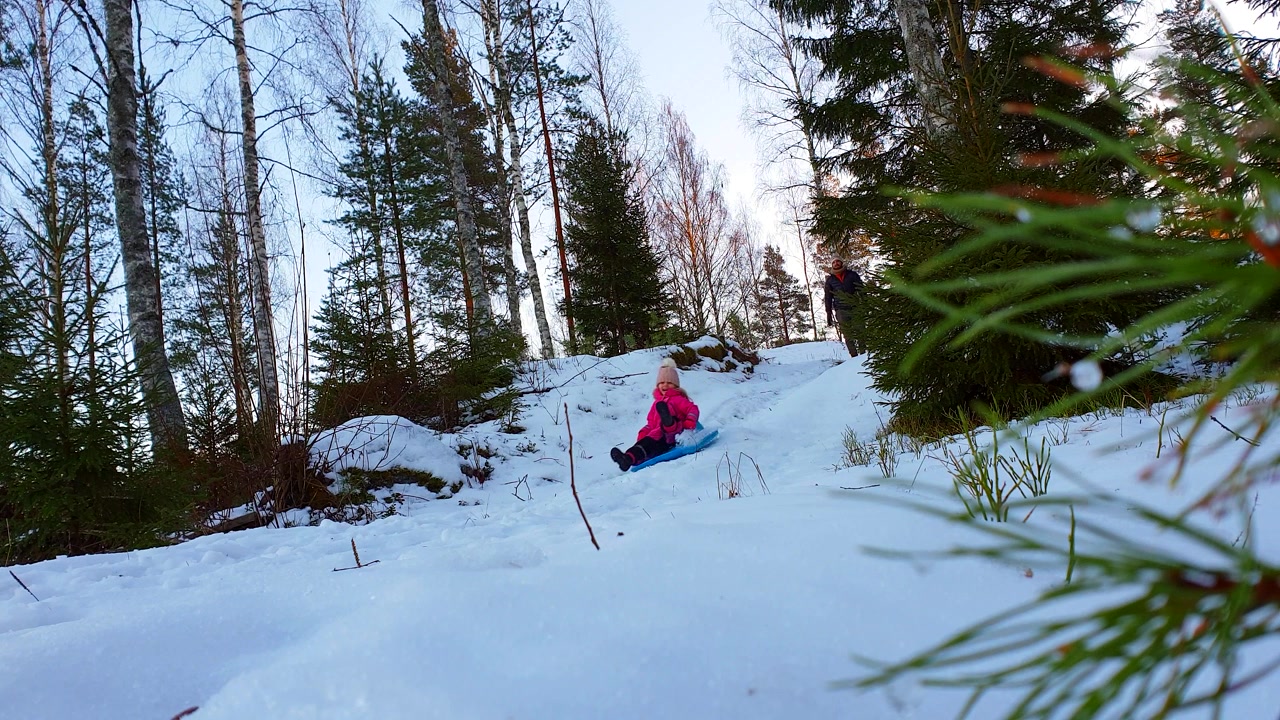 SLOW MOTION: papà e figlia che vanno in slitta nella foresta invernale.