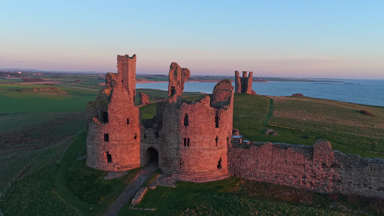 Luftfoto af Dunstanburgh slotsruiner ved solopgang
