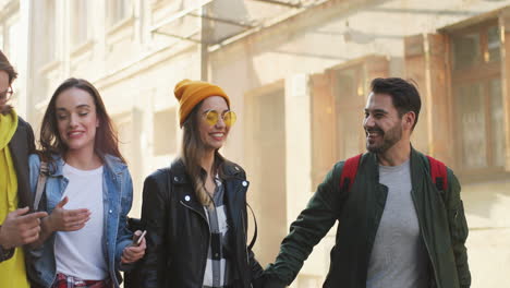 jóvenes amigos caucásicos caminando por la calle y hablando en un agradable día soleado en la ciudad