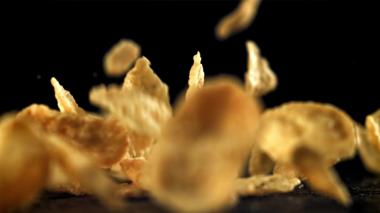 Cornflakes Dourados Caindo em Câmera Lenta em um Fundo Preto