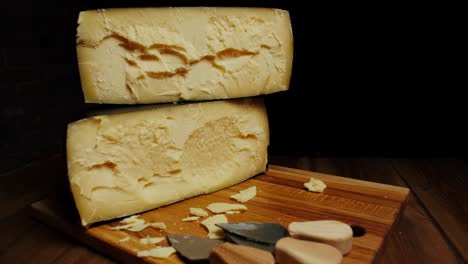 medium hard cheese head parmesan on wooden board, with cheese parmesan knifes. slide shot