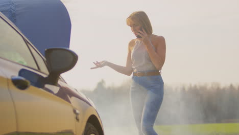 frustrated woman with broken down car on country road calling for help on mobile phone