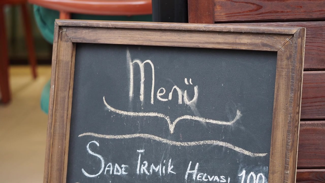Håndskrevet menu på et kridttavleskilt uden for en café.