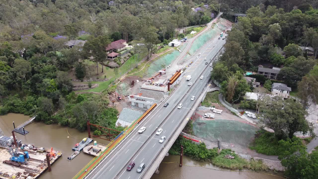 4K Drone footage of a construction site of a new bridge over a river next to an existing highway bridge