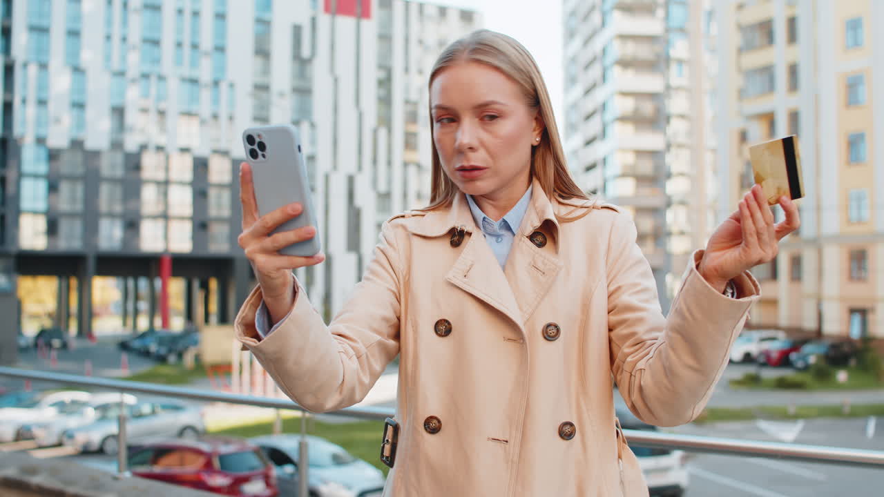 Frustrated mature businesswoman girl using credit card and mobile phone on downtown city street
