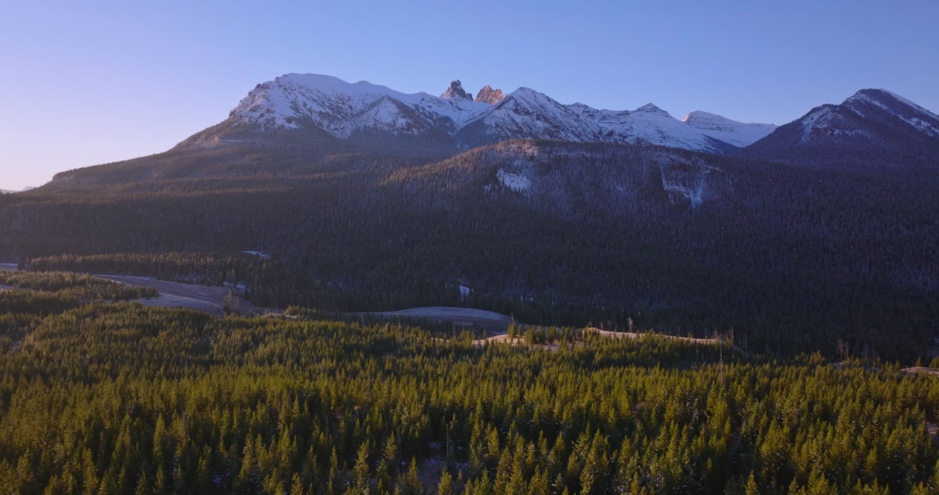 Wide mountain valley with forest and distant peaks near Cooke City Montana, aerial soothing establishing dolly
