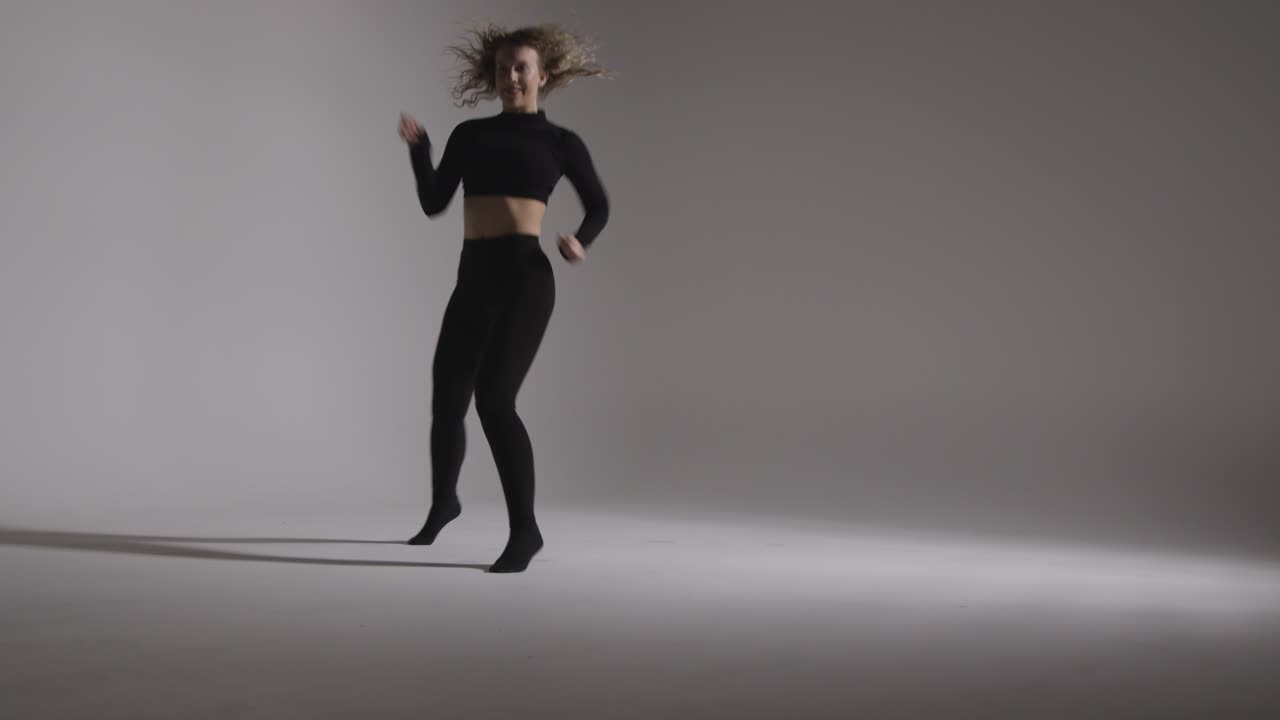 Full Length Studio Shot Of Young Woman Doing Dance Practise Against Grey Background
