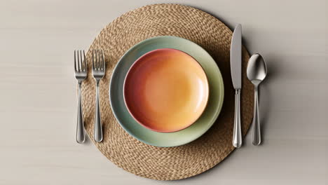 a perfectly set table with colorful plates and cutlery on a woven placemat