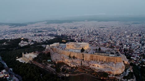 drone aéreo de 4k filmado sobre la acrópolis de atenas y el odeón de herodes por la noche