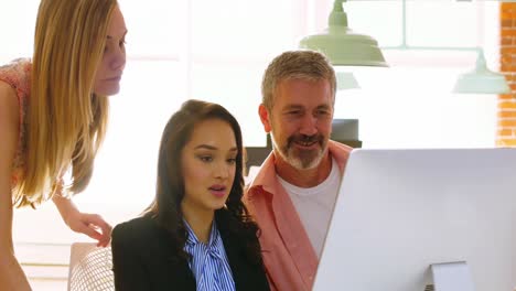 Male-and-female-executives-discussing-over-computer