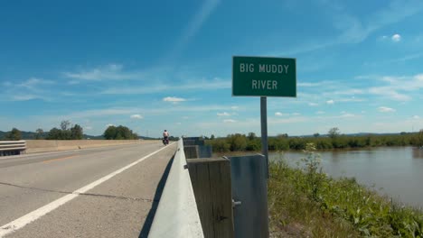 cyclist bikepacking across bridge over river, still shot