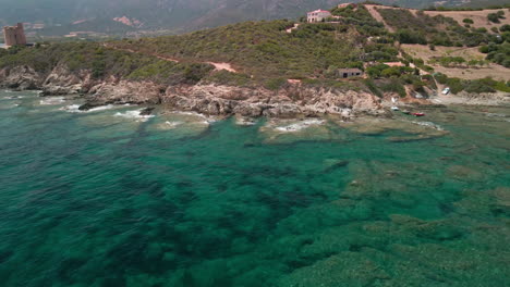 vista panorámica de la costa en el mar mediterráneo azul con rocas y vegetación en segundo plano en cerdeña, italia - órbita aérea de drones
