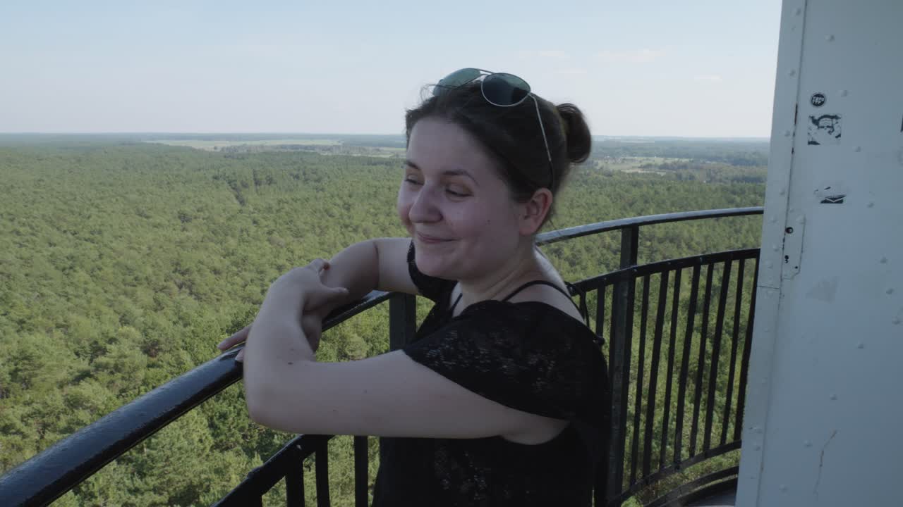 una mujer admira la vista panorámica del bosque verde exuberante y el mar desde la cima del faro de stilo en stilo, polonia