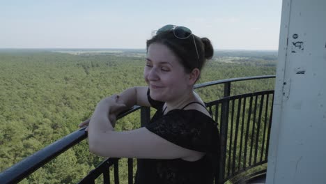 a woman admires the panoramic view of the lush green forest and the sea from the top of the stilo lighthouse in stilo, poland