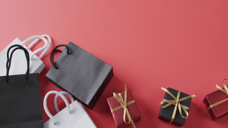video of gift bags and gift boxes with ribbon and copy space on black background