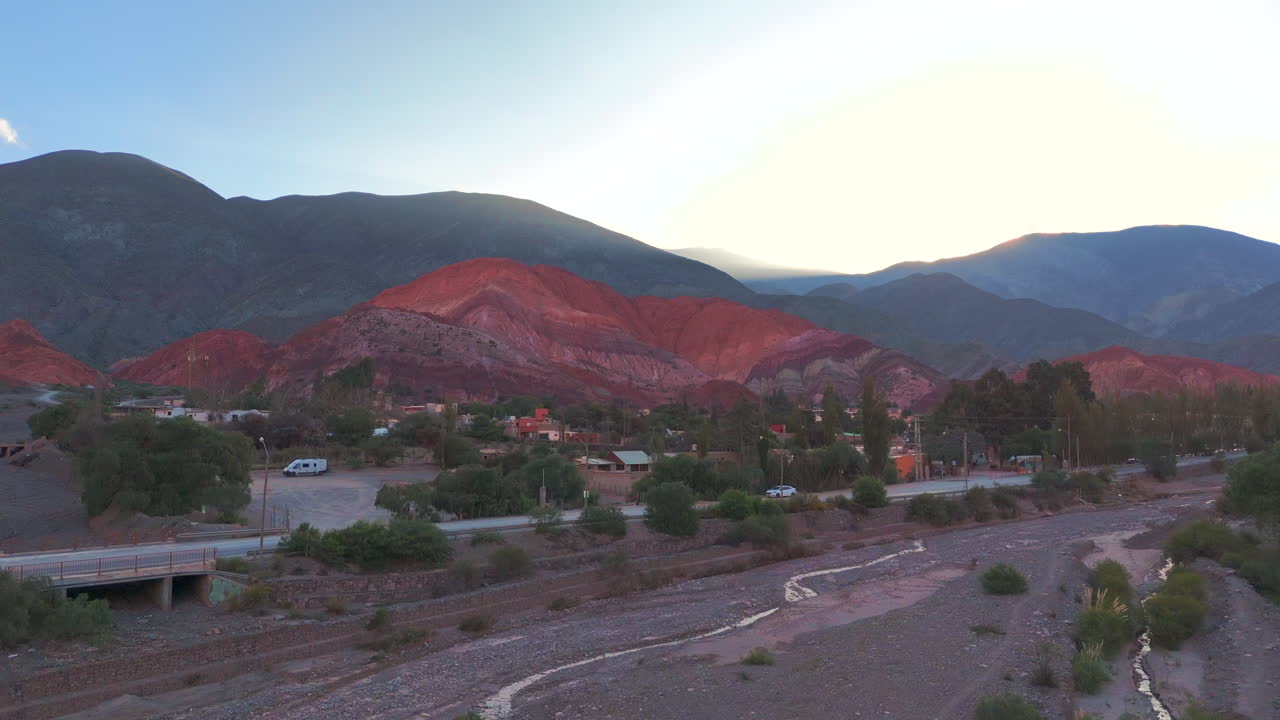 drone avanzando sobre un lecho de río seco y revelando el pintoresco pueblo de purmamarca con su famoso "cerro de los 7 colores"