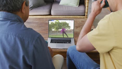 video de padre e hijo sentados en el sofá y viendo un partido de fútbol en la computadora portátil