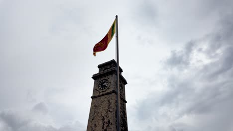 sri lankan flag flying high next to the galle clock tower