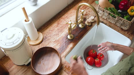 washing fresh tomatoes in kitchen sink, preparing ingredients for healthy meal, at home