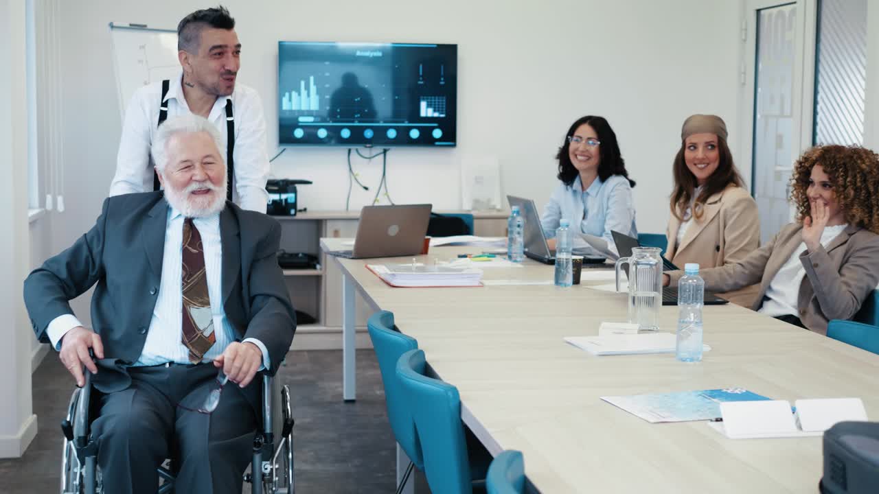 동료가 비즈니스 컨퍼런스 회의가 끝난 후 체어에 앉은 노인 사업가를 밀어 넣습니다.