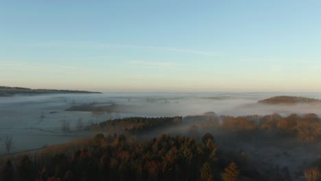 drone reveal of low hanging fog and mist over british countryside in on frosty morning at sunrise