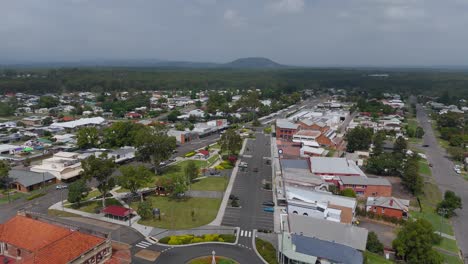 aerial flyover roundabout and cars of kuri kuri town in australia. cloudy dark sky in summer. houses and homes of neighborhood in new south wales. wide shot.