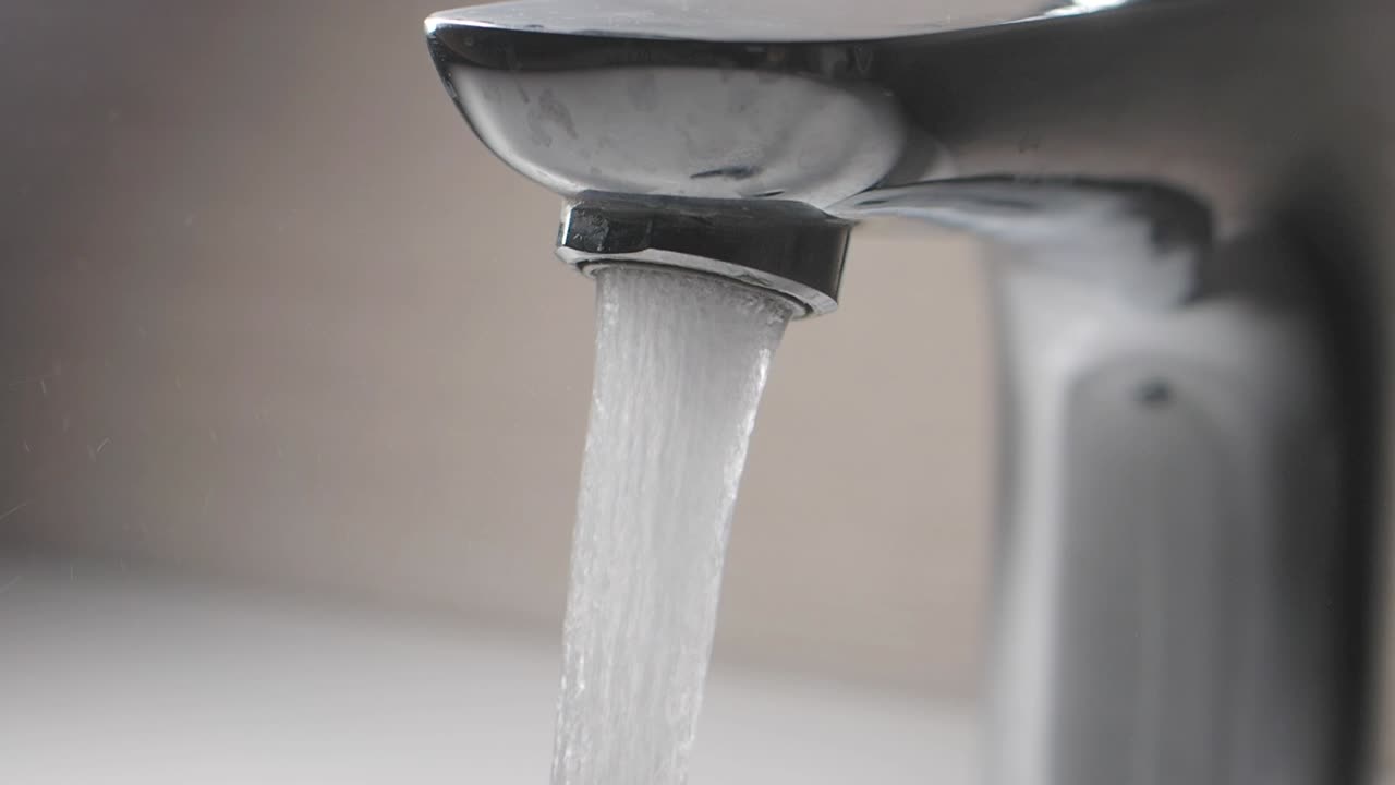 Primo piano dell'acqua che scorre da un rubinetto cromato