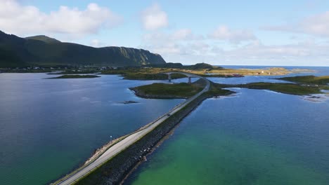 following a car driving across the fredvang bridge in lofoten northern norway with the sea ocean water shimmering in light turquoise blue and green tones on a sunny day in summer