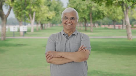 Happy-Indian-old-man-standing-crossed-hands-in-park