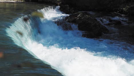 Close-up-of-a-cascading-waterfall,-with-water-flowing-smoothly-over-rocky-ledges-into-a-pool-below