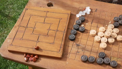 configuración de juego de estrategia tradicional con piezas de madera y juegos de mesa tallados, con damas acompañadas de una copa de arcilla de la época vikinga